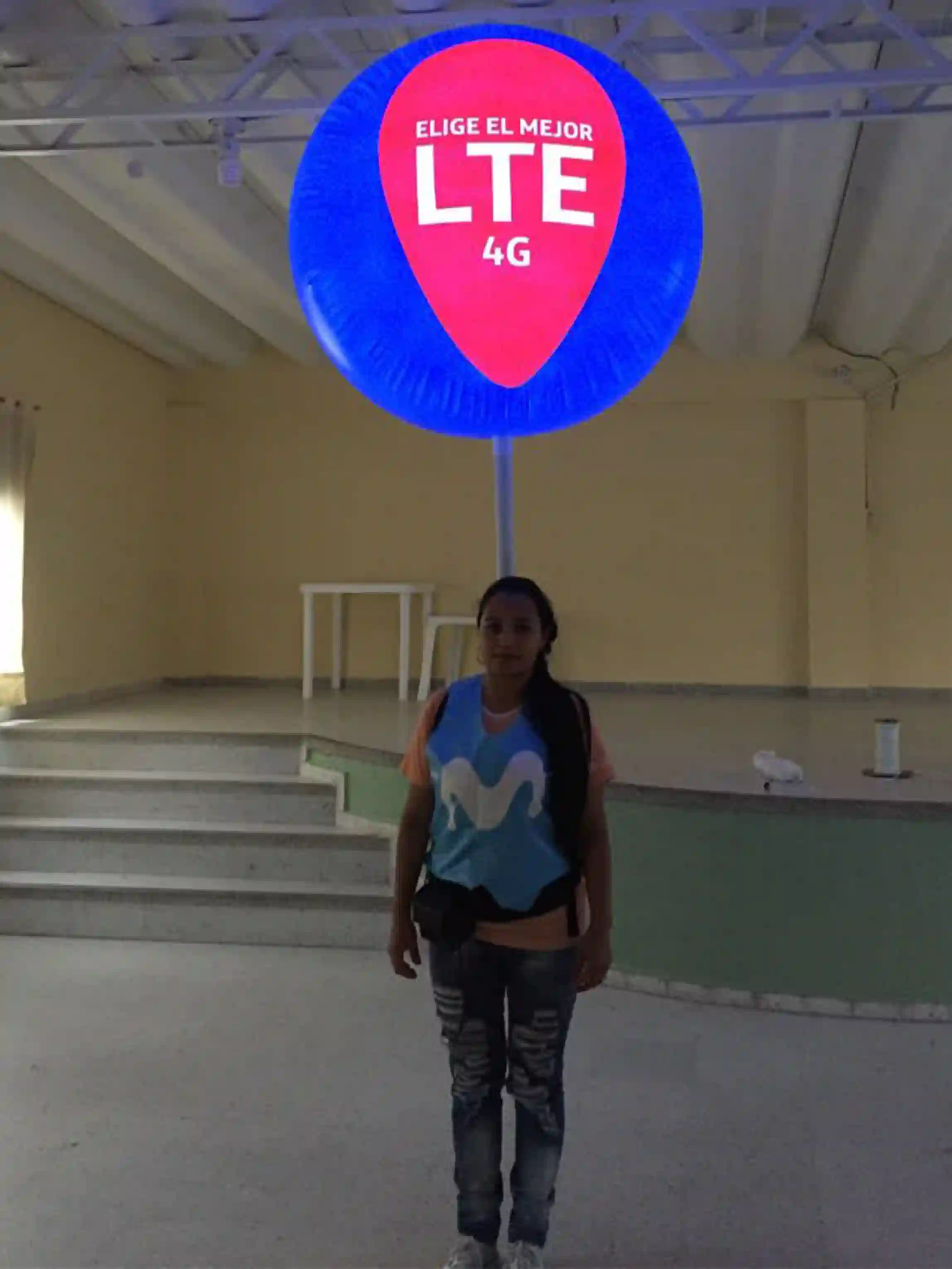 Mujer cargando un globo móvil azul con iluminación interior promocionando la empresa Movistar